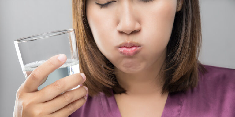 Woman rinsing and gargling while using mouthwash from a glass, During daily oral hygiene routine, Girl in a purple silk robe, Dental Healthcare Concepts