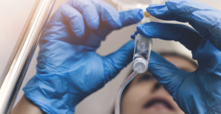 Nurse with blue gloves adjusting IV