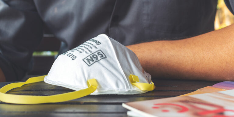 closeup N95 air filter mask. personal protective equipment in office with soft-focus and over light in the background