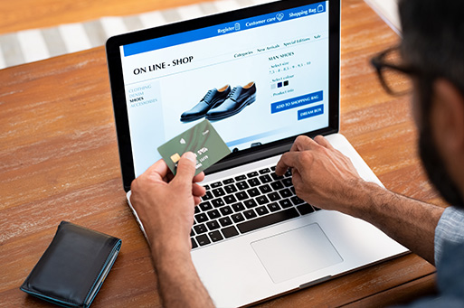 webinar-merchant_monitoring_is_broken Man in front of open laptop with his credit card in his hand.