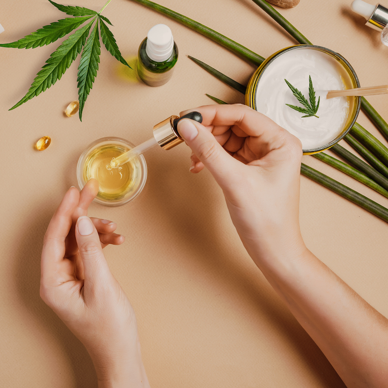 woman with CBD cosmetics, dropping oil on her hand.