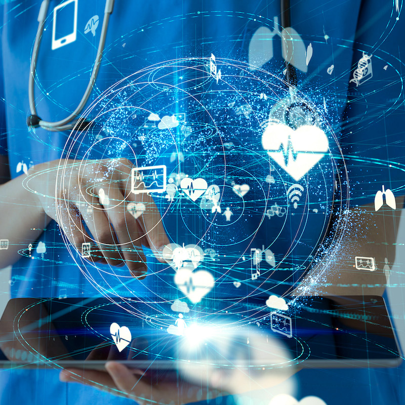 Image of medical professional holding a device with virtual graphics coming out of it and floating in the air.