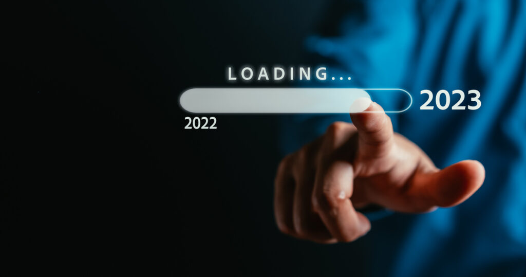 This is an image of a man touching a screen that says loading. The beginning of the loading bar says '2022' and the end says '2023'.