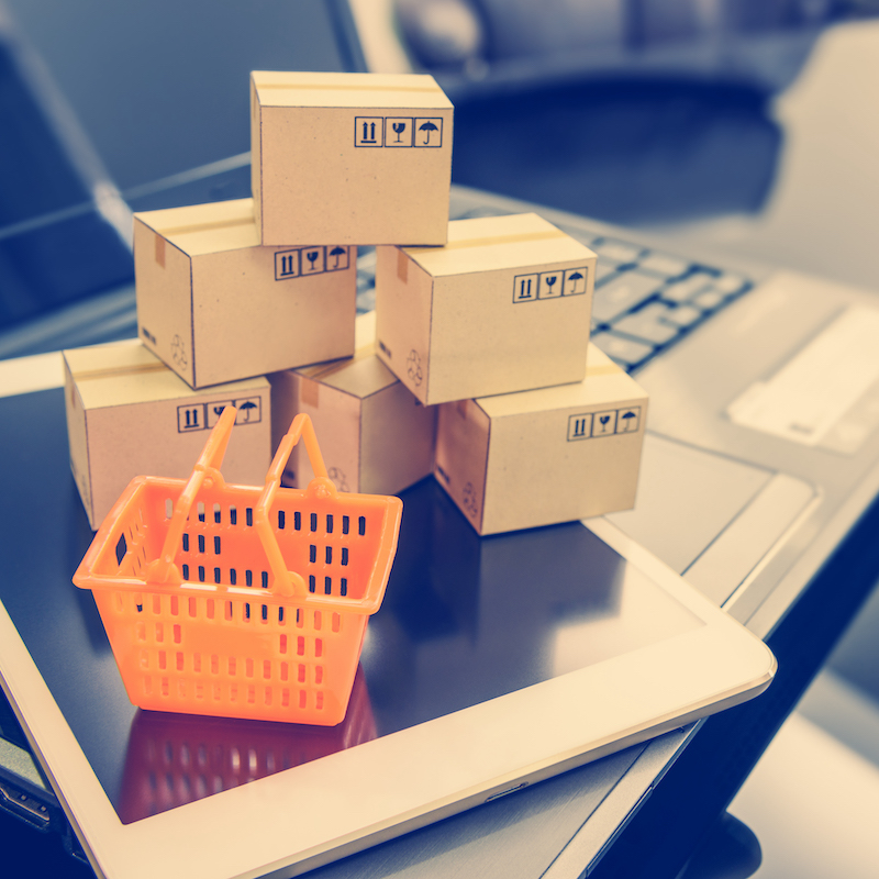 Mini orange shopping basket on a smart device and a laptop with boxes. Concept of shopping that client can buy or purchase goods or products from websites worldwide via internet by just a few clicks. Mini orange shopping basket on a smart device and a laptop with boxes. Concept of shopping that client can buy or purchase goods or products from websites worldwide via internet by just a few clicks.