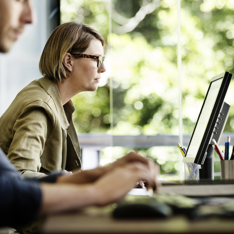 Side view of businesswoman working on computer at desk in office