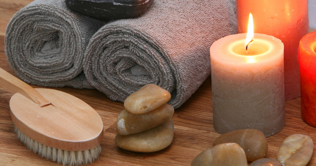 Image of towels, a brush, candles, and warm stones to represent common medical spas.