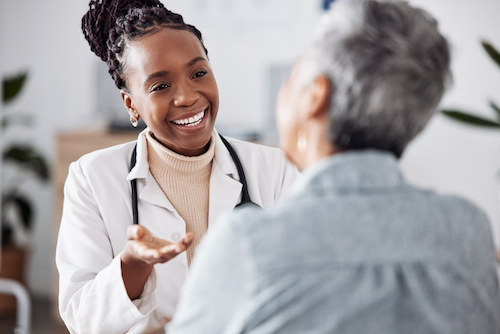 Smile, black woman or doctor consulting a patient in meeting in hospital for healthcare feedback or support. Happy, medical or nurse with a mature person talking or speaking of test results or advice