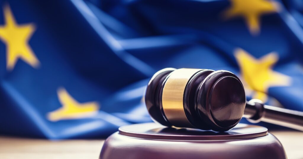 Judges wooden gavel with EU flag in the background. Judges wooden gavel with EU flag in the background. Symbol for jurisdiction.