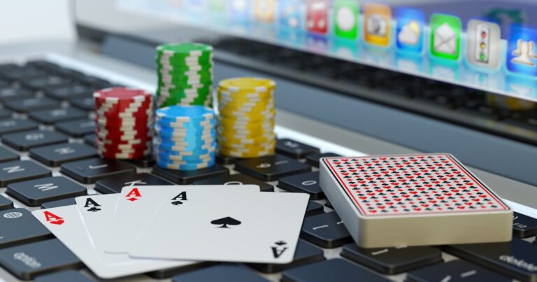 Four aces, deck of playing cards and colorful chips on computer laptop keyboard