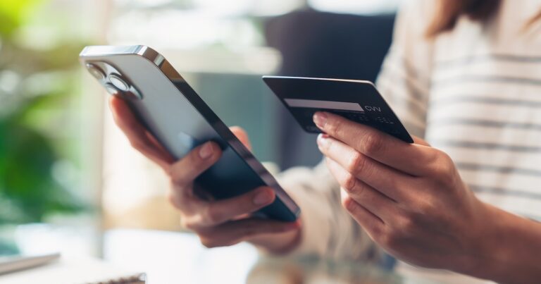 Woman hand holding credit cards and using smartphone for shopping online with payment on internet banking.