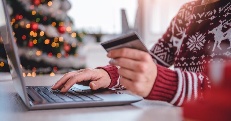 Women wearing red sweater shopping online and using credit card at home office