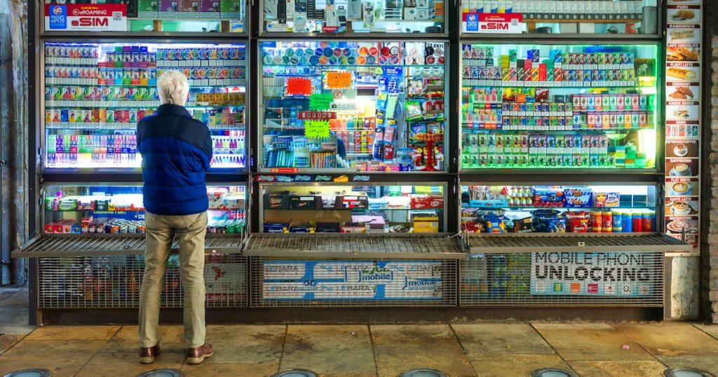 London, UK - 19 May, 2025: a senior man stands looking at a huge selection of disposable vapes at a kiosk in London, UK.
