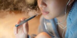 Young woman vaping an electronic cigarette for relax while working at night
