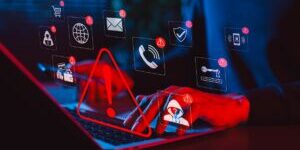 Online scam alert and cybersecurity warning concept. Man holding phone while using laptop, warning sign for scam with icons online threats, phishing, cyber secure, unknown person, suspicious scammer,