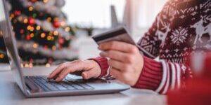 Women wearing red sweater shopping online and using credit card at home office