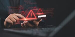 Man use smartphone and laptop with spam virus on warning caution for notification on internet security protect. Ransomware malware attack and data breach.